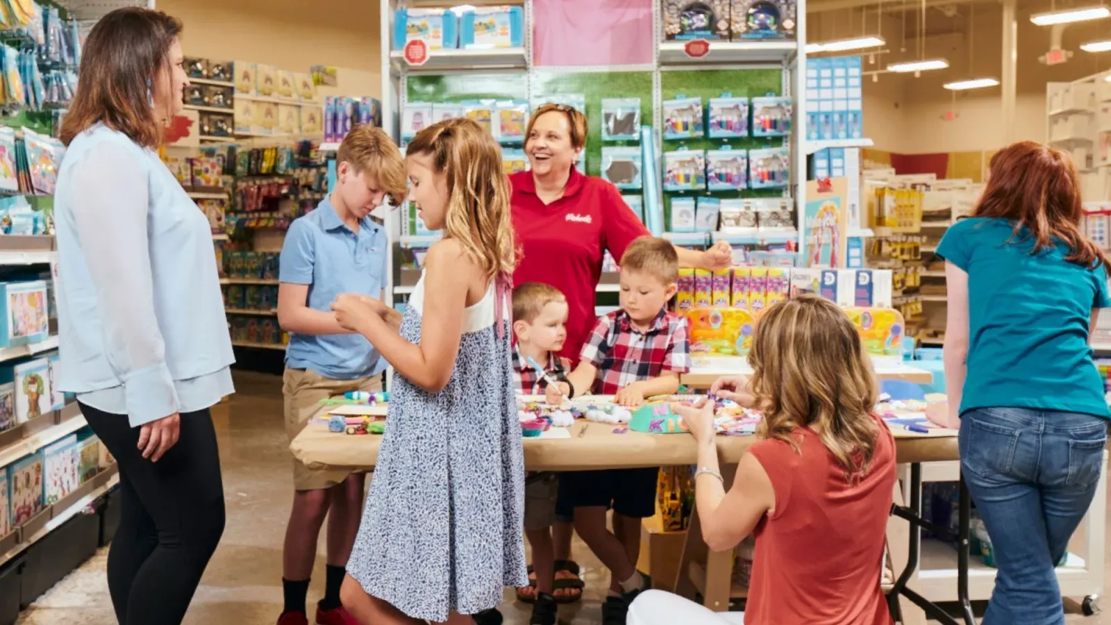 Michaels store associate leading a crafting activity at an in-store table with customers