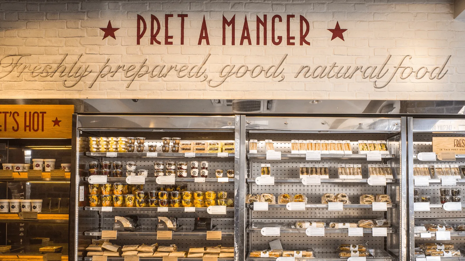 Inside a Pret A Manger location showing the branded food display with freshly prepared sandwiches, salads, and soups