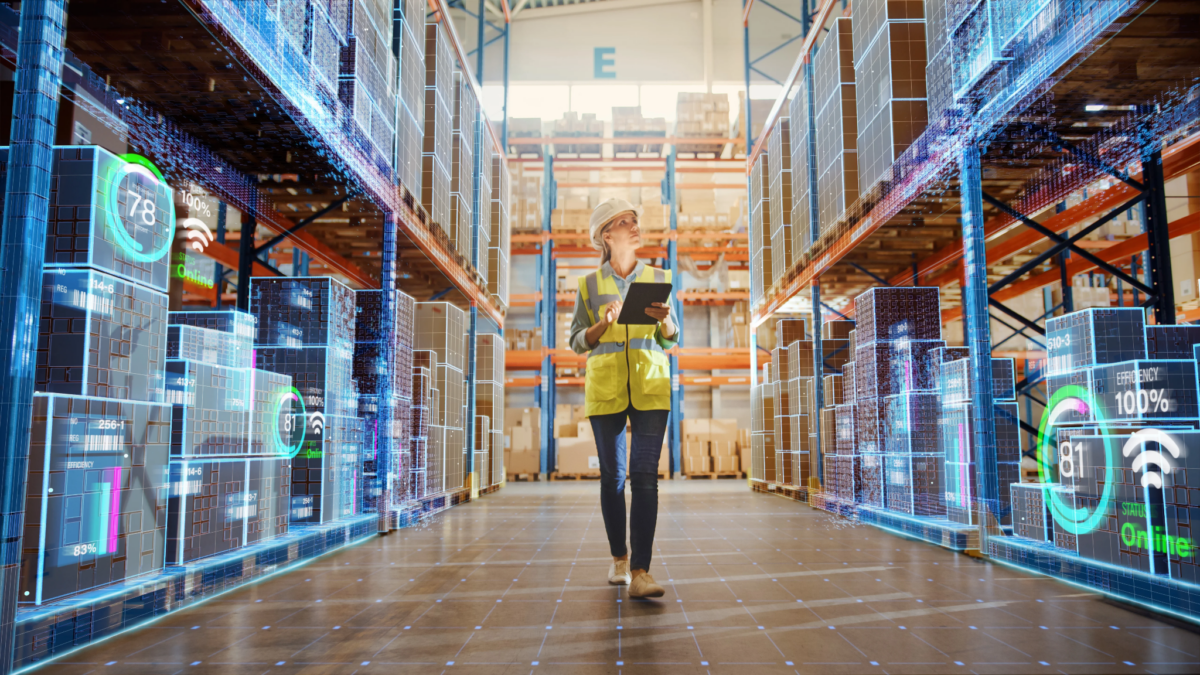 Worker checks stock on a tablet as AI overlays show real-time inventory and efficiency data across warehouse shelving.