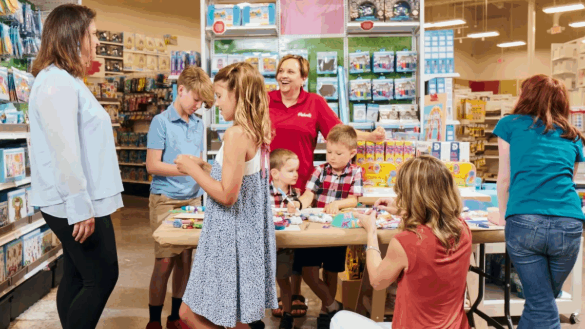 Michaels store associate leading a crafting activity at an in-store table with customers