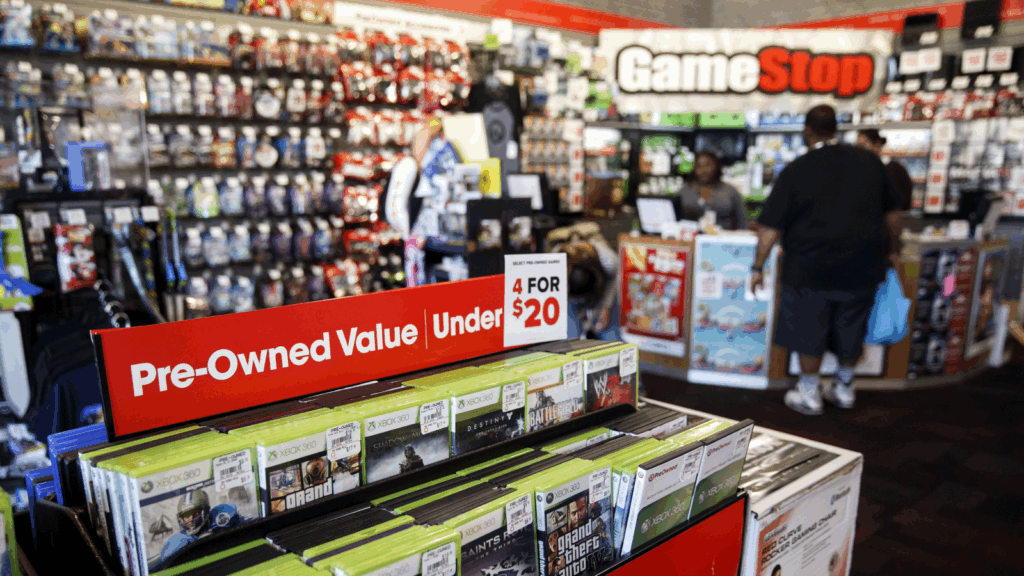 Inside a GameStop store showing product displays and customers browsing pre-owned games
