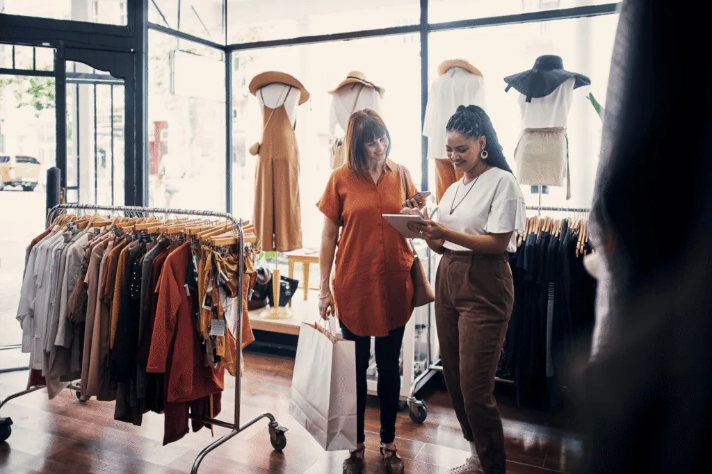 Two store team members reviewing a checklist on a tablet in a clothing store