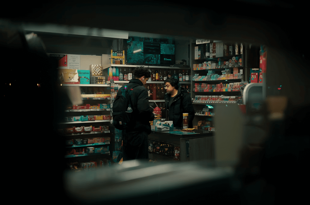 A convenience store at night time with a sole worker and customer