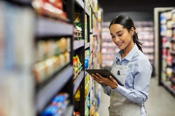 Store associate using a tablet to check task compliance against shelf stock in a grocery aisle