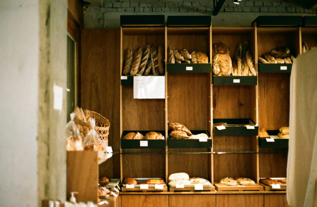 Artisan bakery display wall holding baguettes, boules and pastries in labelled trays.