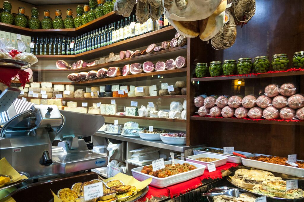 Deli counter with a commercial meat slicer, cured meats, cheeses and prepared foods on display