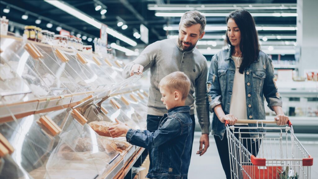 Family choosing bread together in a supermarket bakery section.