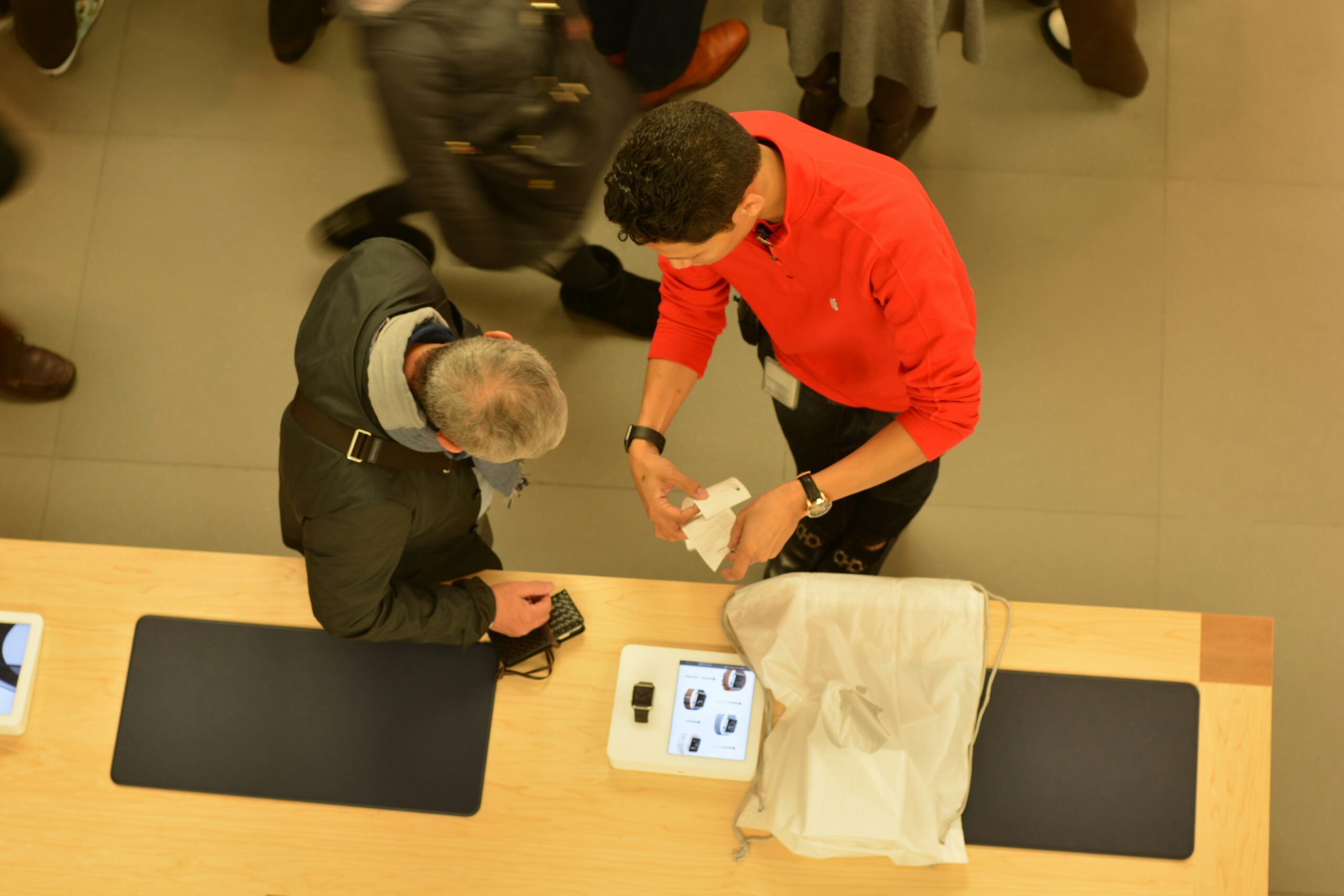 Store associate checking a customer’s receipt at a counter during a busy period in a retail store